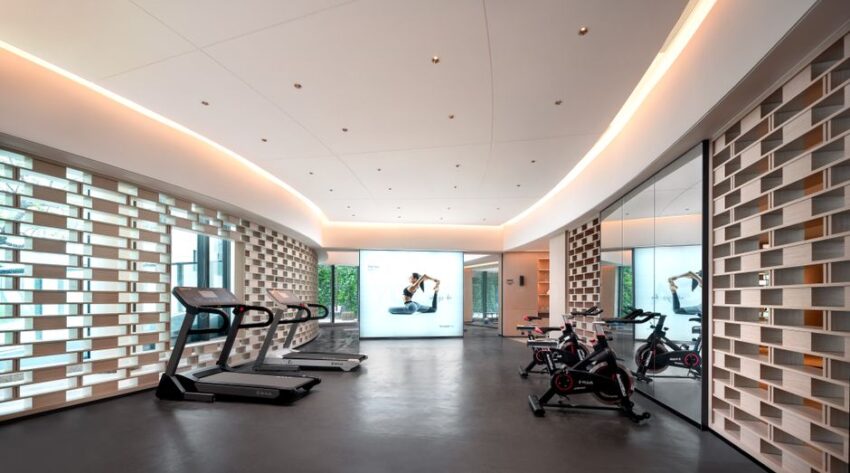 Een persoon die een loopband reset in een moderne fitnessruimte, ideaal voor thuisgebruik.